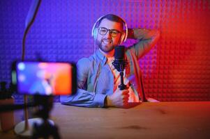 A video blogger records content in his studio. The host of the video blog is a young man who is very enthusiastic about telling his subscribers a story. photo