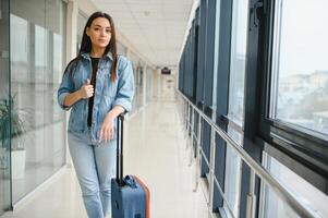 joven mujer tracción maleta en aeropuerto Terminal. Copiar espacio foto