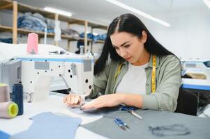 Portrait of a beautiful seamstress carrying a tape measure and working in a textile factory photo