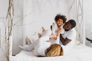 Happy interracial couple with their little daughter at home photo