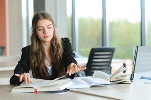 Teen girl studying with textbook writing essay learning in classroom. photo