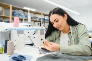 Portrait of a beautiful seamstress carrying a tape measure and working in a textile factory photo