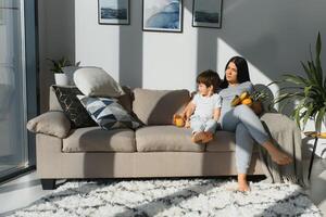 joven madre con su 4 4 años antiguo pequeño hijo vestido en pijama son relajante y jugando en el cama a el fin de semana juntos, perezoso mañana, calentar y acogedor escena. foto