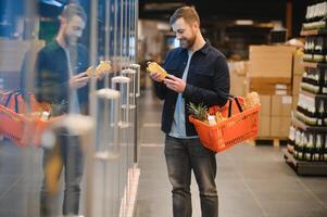 Young man buying groceries at the supermarket. Other customers in background. Consumerism concept. photo