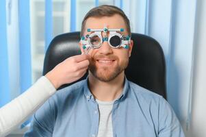 hermoso joven hombre es comprobación el ojo visión en moderno oftalmología clínica. paciente en oftalmología clínica foto