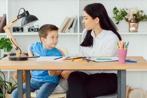 Young female psychologist working with little boy in office photo