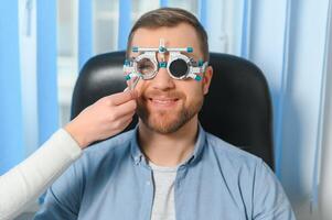 Handsome young man is checking the eye vision in modern ophthalmology clinic. Patient in ophthalmology clinic photo