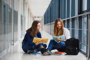 hembra estudiantes sentado en el piso y leyendo notas antes de examen foto