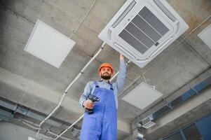 Happy Male Technician Repairing Air Conditioner. photo