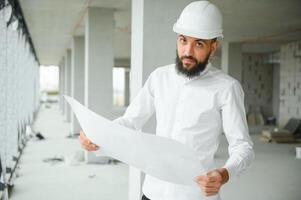 Young attractive arabic industrial engineer in hard hat. Professional and industry, builder architect job, worker checking work at plant indoor photo