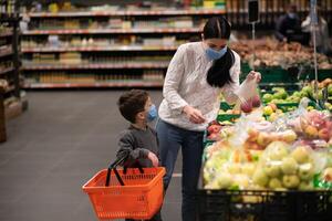 Mother and her son wearing protective face mask shop at a supermarket during the coronavirus epidemic. photo