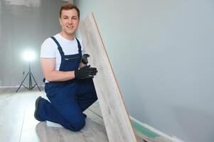 Repairman laying laminate flooring at home photo