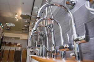 Rows of new faucets in plumbing shop, closeup photo