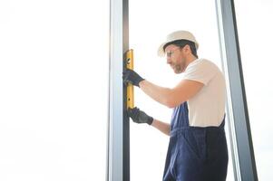 handsome young man installing bay window in new house construction site. photo