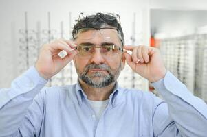 lentes controlar, mayor visión y mayor hombre a un consultante optometría clínica para bienestar. feliz, sonrisa y antiguo cara con lente, marco y gafas elección en un Tienda para ayuda consiguiendo un prescripción. foto