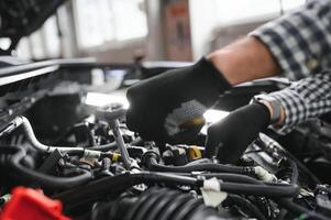 Mechanic examining under hood of car at the repair garage photo