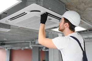 Happy Male Technician Repairing Air Conditioner photo