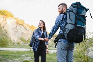 Pareja disfrutando hermosa puntos de vista en el montañas, mientras de viaje con mochilas en el montañas durante el verano vacaciones foto