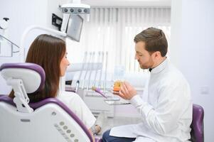 The concept of diagnosis and treatment of tooth disease. Doctor shows a model of a sick tooth. photo