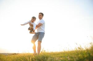 del padre día. contento familia padre y niñito hijo jugando y riendo en naturaleza a puesta de sol foto