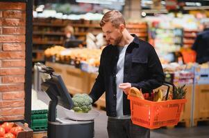 Portrait of smiling man walking with his trolley on aisle at supermarket. photo