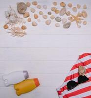 Beach accessories. Towel, flip-flops, starfish, boat and sunglasses on wooden background. Top view with copy space. Sunny toned photo