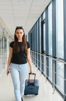 joven mujer tracción maleta en aeropuerto Terminal. Copiar espacio foto