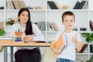 tutor deals with the preschooler with a laptop, a real home interior, the concept of childhood and learning photo