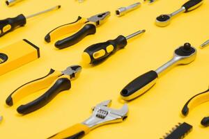 Tools top view on yellow background. Plier, open wrenches, screwdrivers and staple gun flat lay with copy space photo