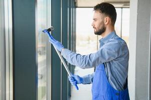 masculino portero limpieza ventana en oficina foto