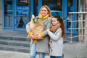 familia compras. madre y su hija son participación tienda de comestibles compras bolso con vegetales foto