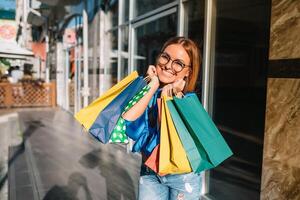 Beautiful girl with shopping bags is looking at camera and smiling while doing shopping in the mall photo