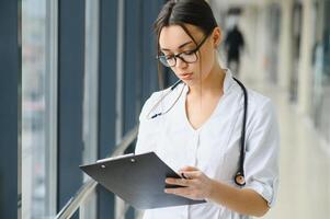 Happy young female doctor wear uniform, white medical coat, stethoscope. Portrait of beautiful female doctor, therapist, nurse. photo