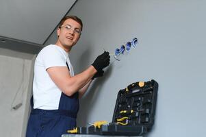 electricista a trabajo en interruptores y enchufes de un residencial eléctrico sistema. foto