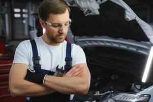 Muscular car service worker repairing vehicle. photo