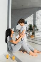 Young mother with her 4 years old little son dressed in pajamas are relaxing and playing in the bedroom at the weekend together, lazy morning. photo