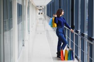 Fashion Shopping Girl Portrait. Beauty Woman with Shopping Bags in Shopping Mall. Shopper. Sales. Shopping Center photo