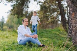 Happy family Mother with son child playing having fun together on the grass in sunny summer day, life moment photo