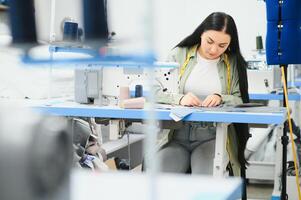 Positive young woman sewing with professional machine at workshop. photo