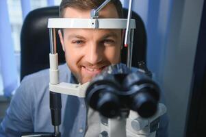 hermoso hombre consiguiendo un ojo examen a oftalmología clínica. comprobación retina de un masculino ojo de cerca foto