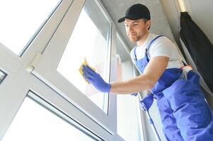 Young man cleaning window in office photo