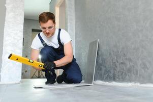 Worker installing ceramic tile on floor near wall. photo