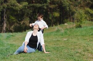 contento familia joven madre y su cinco año antiguo hijo gasto hora al aire libre en un verano día. concepto de familia chico y contento infancia. de la madre día. foto