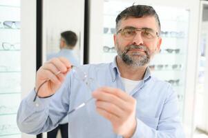 male customer choosing glasses in optics store photo