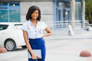 Beautiful black woman using tablet computer in urban background. Successful woman concept. photo