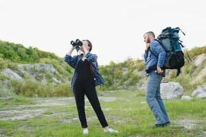 un Pareja de turistas en hora de viaje acero y admirar el hermosa montaña escenario. el chico abrazos el muchacha. el concepto de amar, sensibilidad y recreación foto