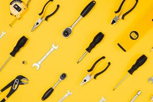 Tools top view on yellow background. Plier, open wrenches, screwdrivers and staple gun flat lay with copy space photo