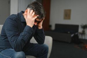 Middle age grey-haired man stressed sitting on sofa at home photo