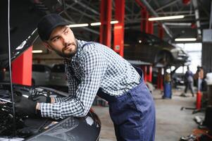 Mechanic examining under hood of car at the repair garage photo