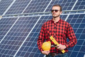 joven técnico instalando solar paneles en fábrica techo foto